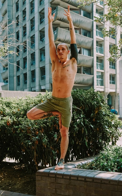 白天站在绿色植物旁穿着棕色短裤的赤裸上身男人